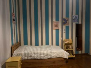 a bedroom with a bed and a striped wall at Green Rooms in Batumi