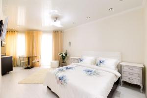 a white bedroom with a large bed and a desk at Apartment Lev Tolstoi in Chişinău
