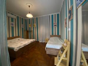 a bedroom with two beds in a room with striped walls at Green Rooms in Batumi