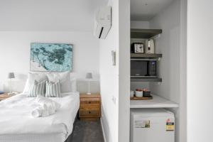 a bedroom with a bed with white sheets and a microwave at Bay View Alfresco in Lorne