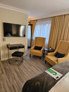 a hotel room with a bed and two chairs and a television at Business & More Boutique Hotel Hamburg in Hamburg