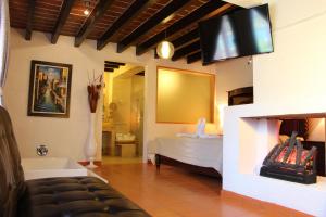 1 dormitorio con 1 cama y TV en la pared en La Capilla Hotel Boutique en Valle de Bravo