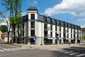 a white building on the corner of a street at Aura apartamentai in Druskininkai