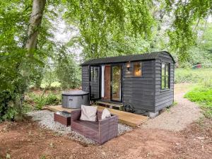 a black tiny house with a bench and a grill at Coastal Views in Cloughton