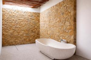 a bath tub in a bathroom with a stone wall at Segara Hill Villa in Senggigi