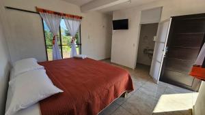 a bedroom with a red bed and a bathroom at Hospedaje Tecmilco in Tepoztlán