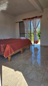 a bedroom with a bed with a red comforter at Hospedaje Tecmilco in Tepoztlán