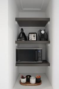 a kitchen with a black microwave on shelves at Bay View Ocean Breeze in Lorne