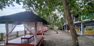 a group of benches with an umbrella on the beach at Lantau Beach Resort in Tukuran