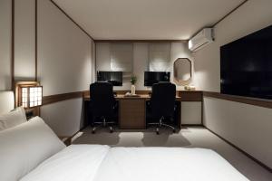 ein Schlafzimmer mit einem Bett und zwei Stühlen und einem Schreibtisch in der Unterkunft Hotel Flow-er in Kangnŭng-yŏk