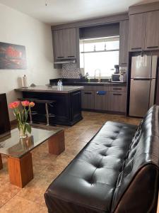 ein Wohnzimmer mit Ledersofa und eine Küche in der Unterkunft Loft B in Mexicali