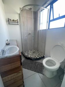 a bathroom with a shower with a toilet and a sink at Forest Gate Apartments and Rooms in Plettenberg Bay