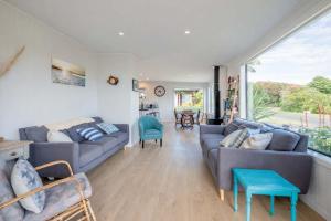 a living room with two couches and a large window at Pohara's Beach Escape in Pohara