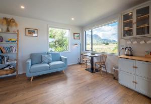 a living room with a blue chair and a table at Pohara Beach Pukeko Studio in Pohara
