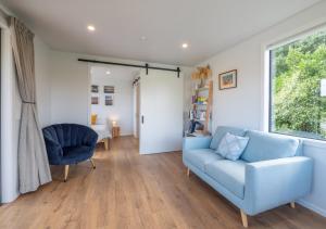 a living room with a blue couch and a window at Pohara Beach Pukeko Studio in Pohara