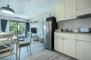 a kitchen with a stainless steel refrigerator and a table at Studio Apartment by the Sea E413 in Phuket