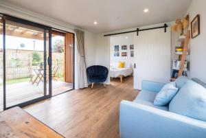 a living room with a blue couch and a bedroom at Pohara Beach Pukeko Studio in Pohara