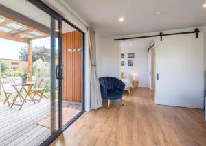 a living room with a sliding glass door and a chair at Pohara Beach Pukeko Studio in Pohara