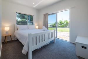 a bedroom with a white bed and a large window at Pohara's Beachside Gem in Pohara