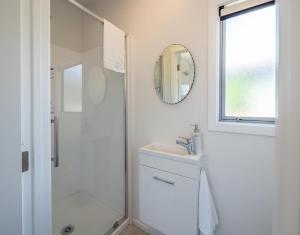 a bathroom with a shower and a sink and a mirror at Pohara's Beachside Gem in Pohara +3 photos