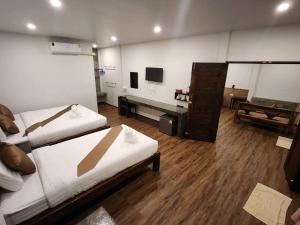 a room with two beds and a tv in it at Bu-Gaan Sukhothai Village in Sukhothai