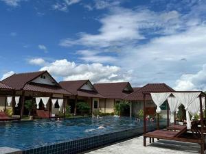 a swimming pool with people in the water at Bu-Gaan Sukhothai Village in Sukhothai