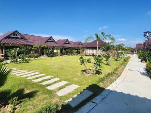 a grassy yard with houses in the background at Bu-Gaan Sukhothai Village in Sukhothai
