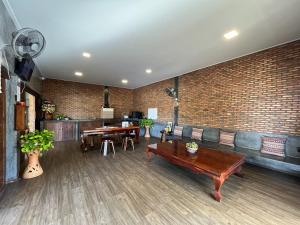 a room with a couch and tables and a brick wall at Bu-Gaan Sukhothai Village in Sukhothai