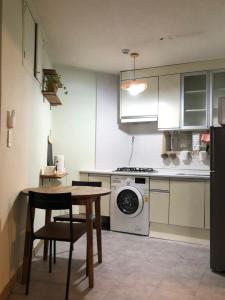 a kitchen with a table and a washing machine at 산초리니 Sanchorini in Busan +4 photos