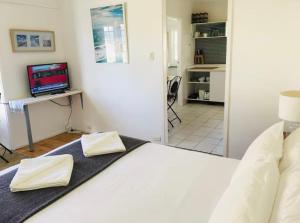a bedroom with a white bed and a television at Ocean Studio along Shelly Beach in Sydney
