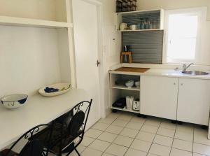 a kitchen with white cabinets and a sink and a chair at Ocean Studio along Shelly Beach in Sydney +8 photos