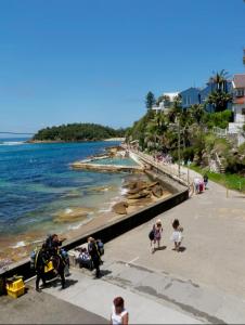 a group of people walking along a beach at Ocean Studio along Shelly Beach in Sydney