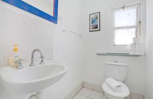 a white bathroom with a sink and a toilet at Ocean Studio along Shelly Beach in Sydney