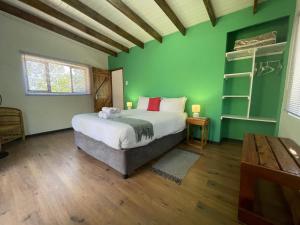 a bedroom with a bed and a green wall at Forest Gate Cabins in Plettenberg Bay