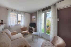 a living room with a couch and a tv and windows at Gîte paumajoly in Castres