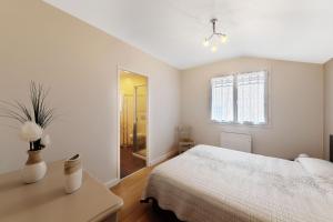 a white bedroom with a bed and a window at Gîte paumajoly in Castres
