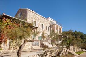 an old stone building with trees in front of it at Stone House Villa Darinka in Vela Luka
