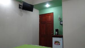 um quarto com uma porta e uma televisão na parede em Mountain Faro Hotel em Monteverde
