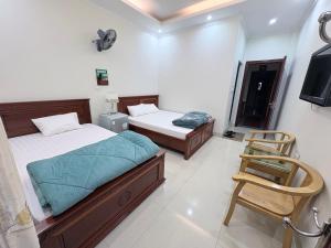 two beds in a room with a chair and a television at Ninh Binh Friendly Hotel in Ninh Binh