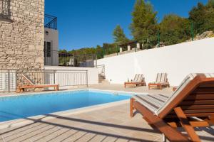 a swimming pool with two lounge chairs next to a house at Stone House Villa Darinka in Vela Luka