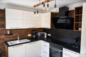 a kitchen with white cabinets and a sink at Hidden Gem Near the Moselle River in Grevenmacher +15 photos