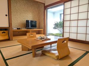 a living room with a wooden table and chairs at Green Rich Hotel Suizenji in Kumamoto