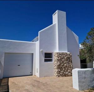 a white house with a garage and a stone wall at Fisherman's Rest in Paternoster