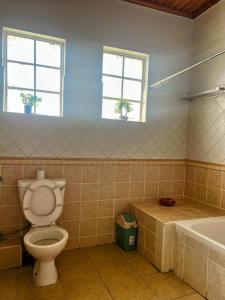 a bathroom with a toilet and a tub and two windows at Westbreeze Residences in Nairobi