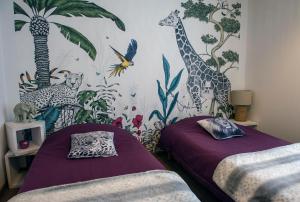 a bedroom with two beds and a mural of giraffes at LE NID DES PLANCHETTES - Suite Chambres d'Hôtes in Germéfontaine