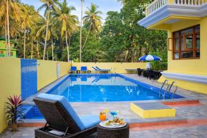 a pool with chairs and a table and a house at Sonikas Leisure in Candolim
