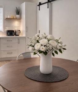 a white vase with white flowers on a table at Pandora Place in Lightning Ridge