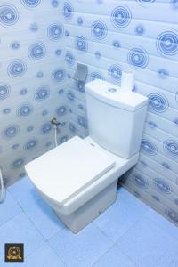 a white toilet in a bathroom with blue swirl wallpaper at Triple W in Watta +4 photos