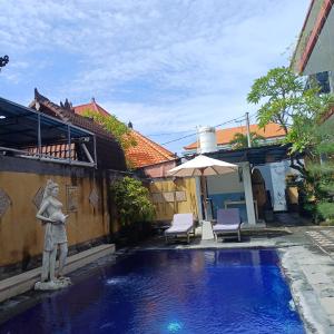 a pool with a statue next to a building at Sanata Yoga Guesthouse in Canggu