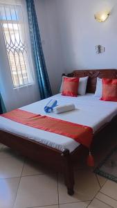 a bed with red and white pillows and a window at Palm Comfort Apartment in Bamburi +6 photos